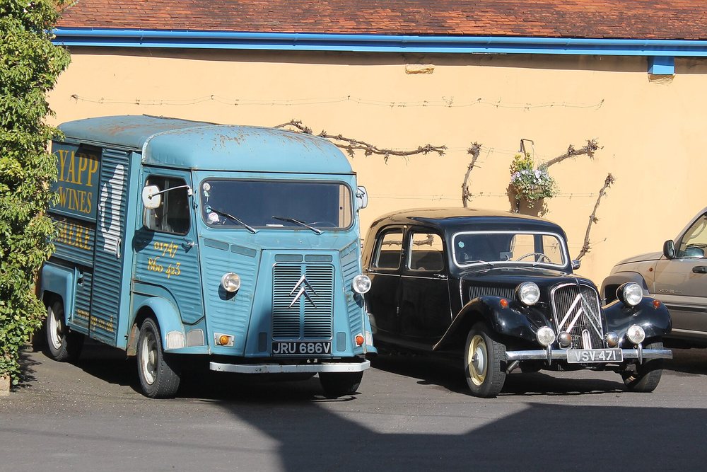A blue Citroën H van beside a black Traction Avant at a club display